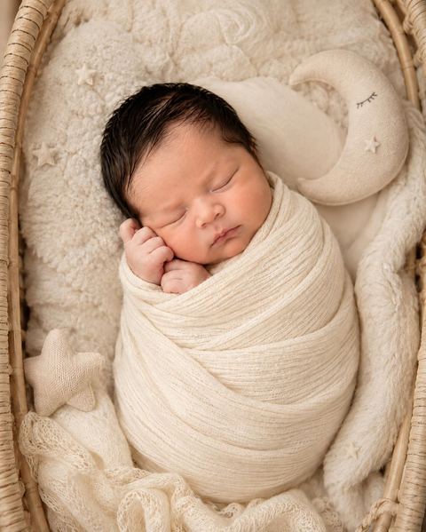 Ensaio newborn com bebê enrolado em manta clara e almofada de lua